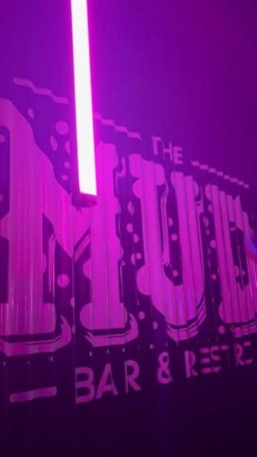A neon tube glowing against a painted bar sign.