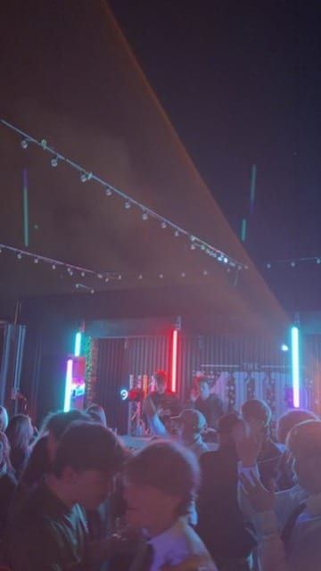 A crowd packed under string lights.