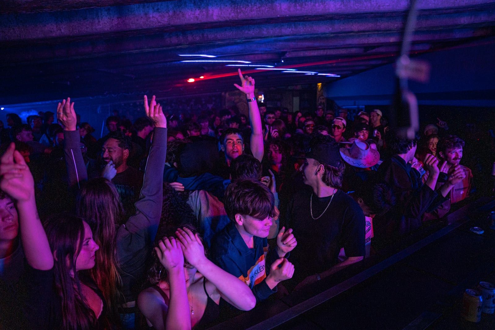 Crowd in purple and blue light, someone mid-jump at the front.