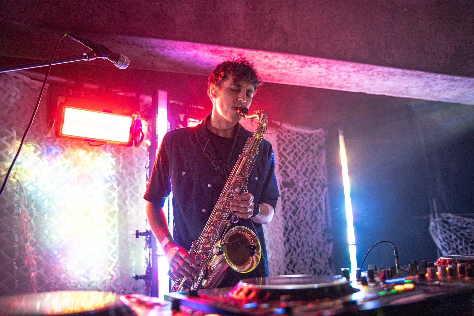 Saxophonist in pink and blue light at the decks.