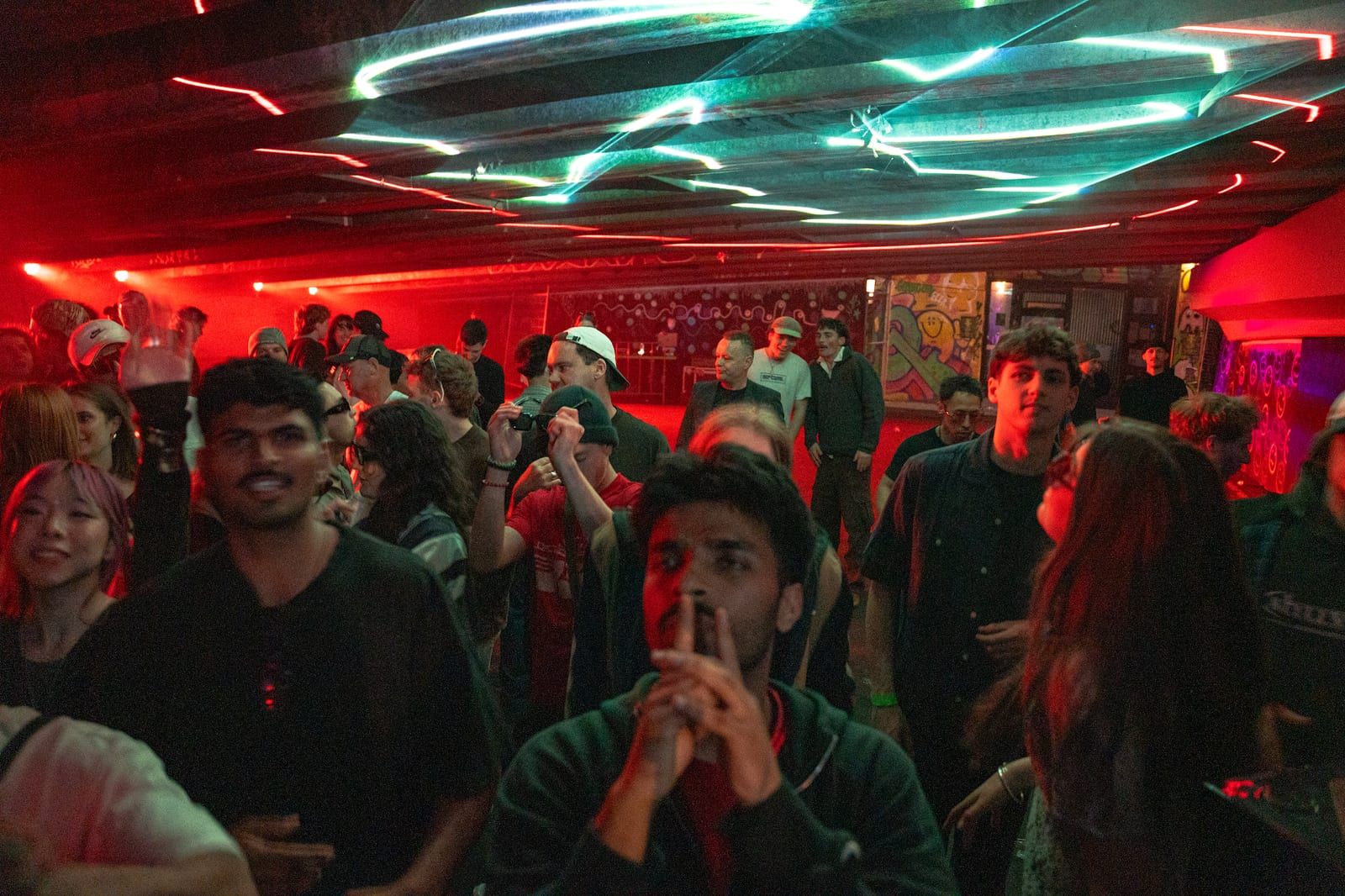 Lasers fanning across the ceiling over a full red-lit crowd.